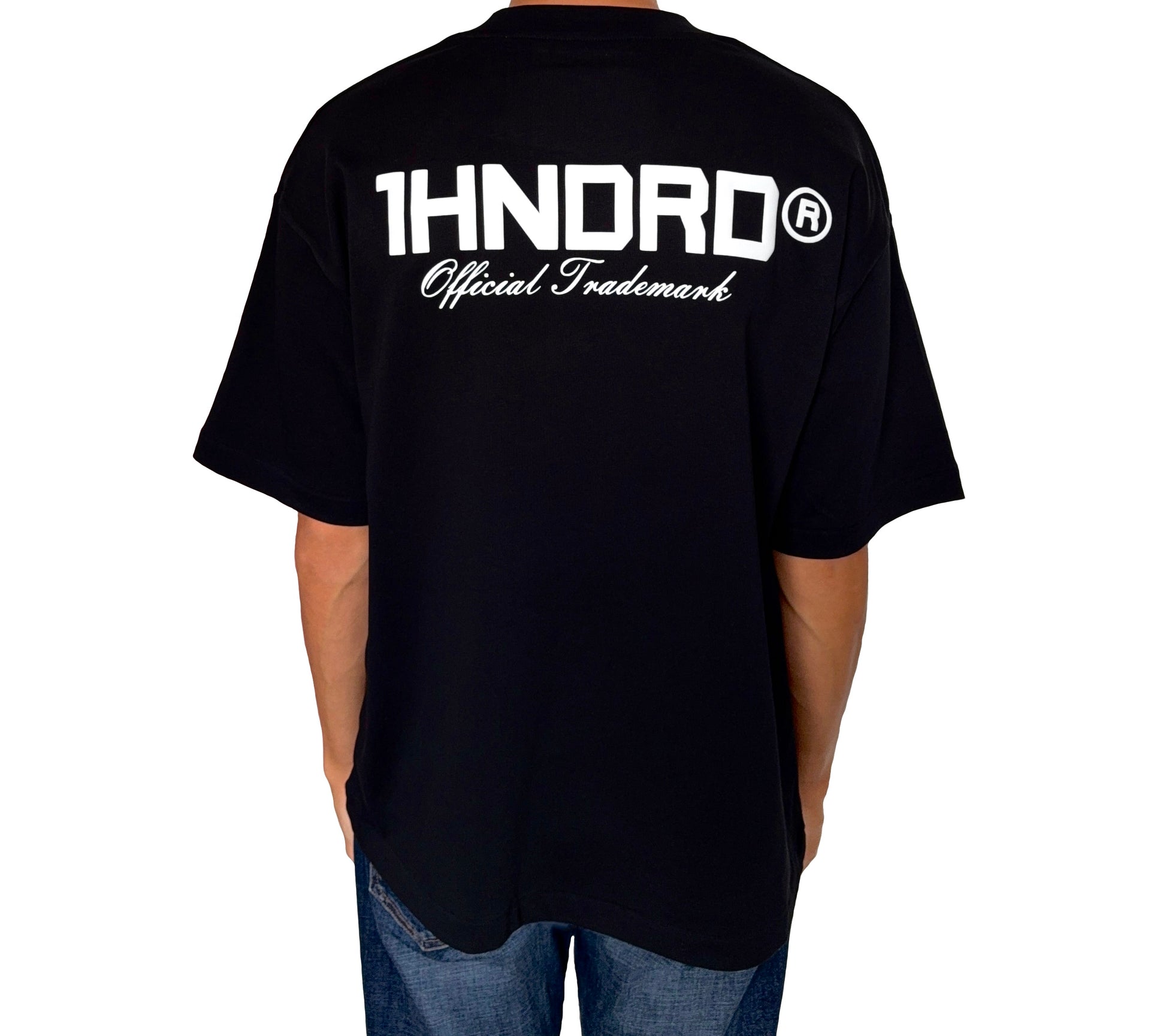 Man standing with back towards camera wearing a 1HNDRD® boxy fit T-shirt in Jet Black with bold puff print – British streetwear